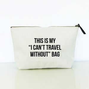 May include: White canvas zippered pouch with black text that reads "This is my "I can't travel without" bag."