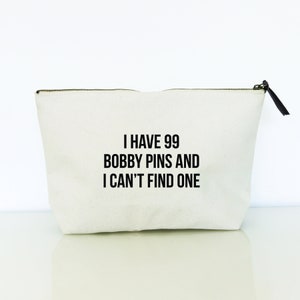 May include: White canvas zippered pouch with black text that reads "I have 99 bobby pins and I can't find one."