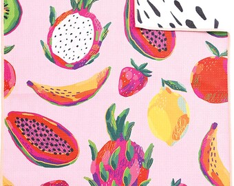 Könnte beinhalten: Ein rechteckiges Handtuch mit hellrosa Hintergrund und einem bunten Muster aus Drachenfrüchten, Erdbeeren, Bananen, Papayas, Zitronen und Kiwischeiben. Die obere Ecke ist umgeschlagen und zeigt eine weiße Rückseite mit schwarzen Strichen.