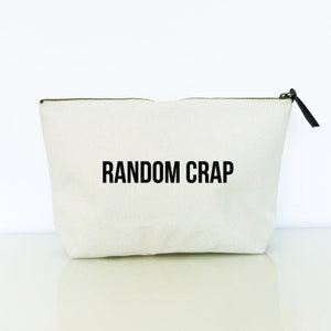 May include: A white canvas zippered pouch with the text "RANDOM CRAP" printed in black.