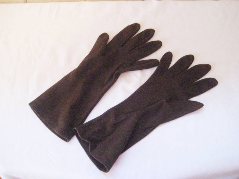May include: A pair of long brown gloves made of a soft fabric.