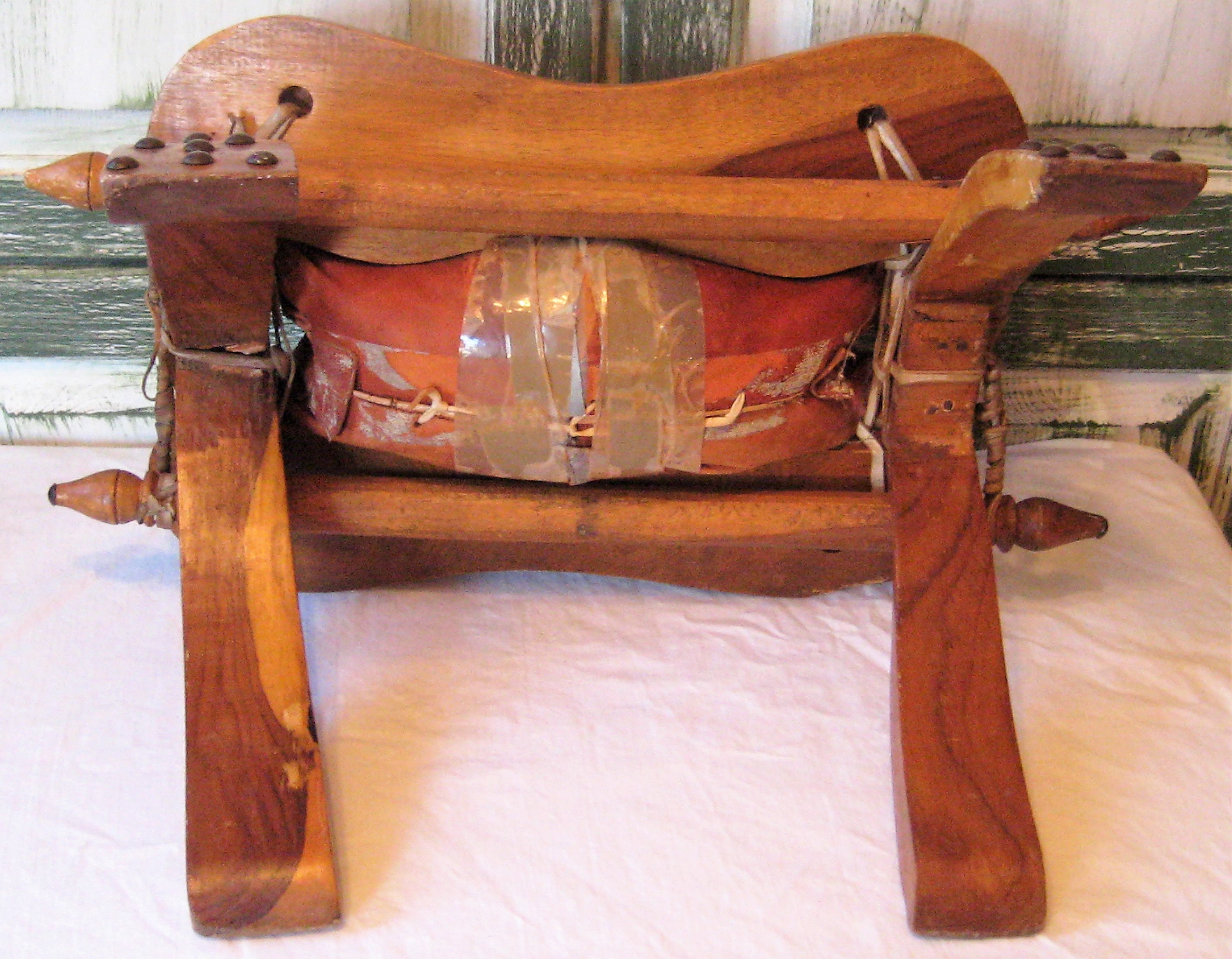 アンティークのラクダの鞍、素朴な木製の足置き、古びた素朴な布張りの