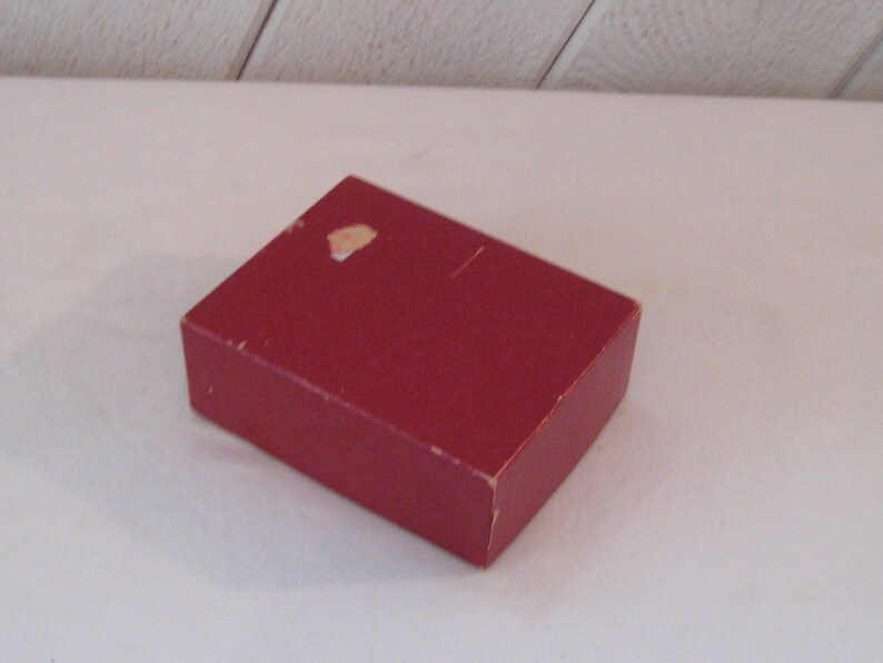 May include: A red cardboard box with a small white mark on the top.