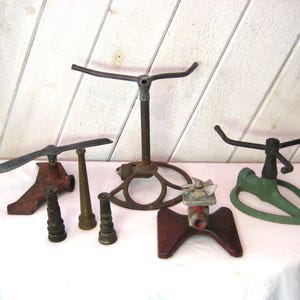Può includere: Una collezione di irrigatori per prato e ugelli in metallo vintage in varie forme e colori. Gli irrigatori includono un design a braccio rotante, una base a treppiede e un modello a ventaglio. Gli ugelli sono in ottone e metallo.