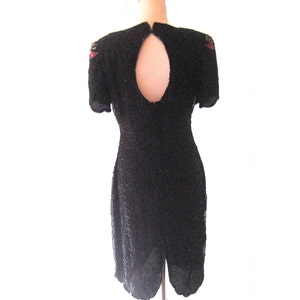May include: A black sequined dress with a keyhole back and short sleeves. The dress has red and gold embellishments on the shoulders.