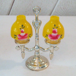 May include: A silver metal lamp base with two yellow lampshades with pink and green floral designs.