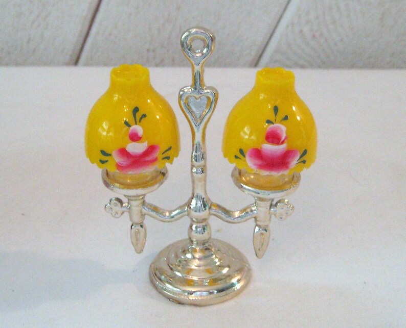 May include: A silver metal lamp base with two yellow lampshades with pink and green floral designs.