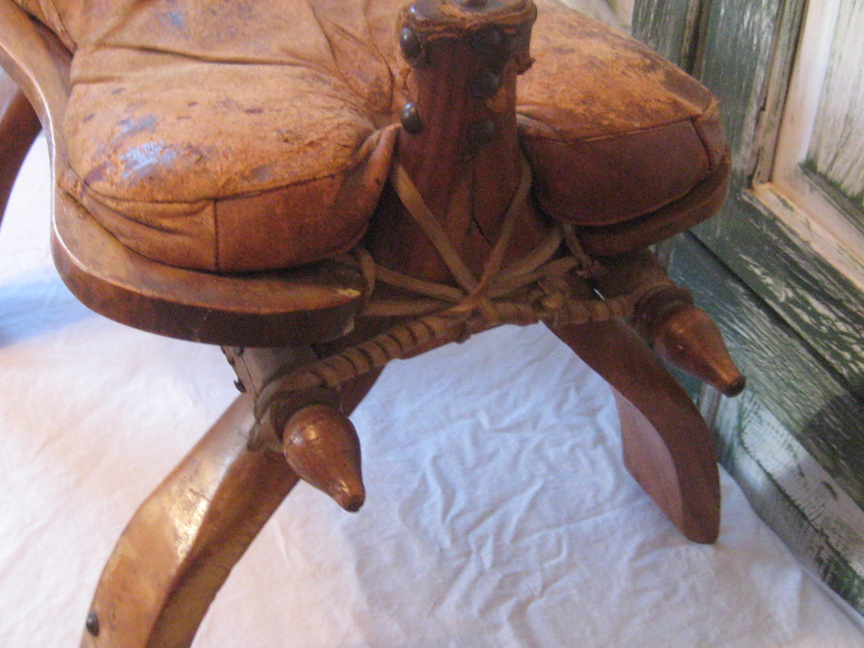 アンティークのラクダの鞍、素朴な木製の足置き、古びた素朴な布張りの