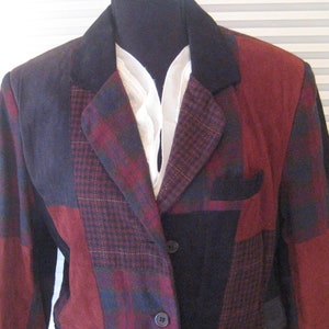 May include: A multi-colored blazer with a patchwork design. The blazer is made of different fabrics, including plaid and solid colors. The blazer has a black collar and two buttons.