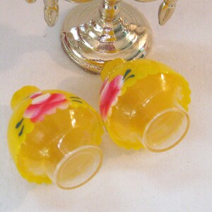 May include: Two small yellow glass salt and pepper shakers with painted pink flowers and green leaves.