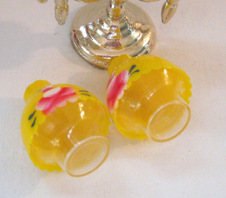 May include: Two small yellow glass salt and pepper shakers with painted pink flowers and green leaves.