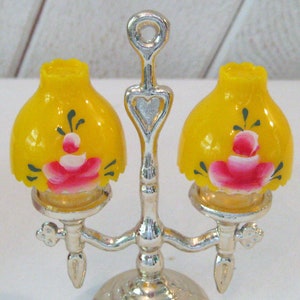 May include: A silver two-light lamp with yellow glass lampshades painted with pink roses and green leaves.