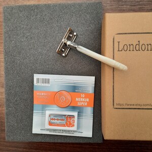 May include: A silver safety razor with a white handle, a package of 10 Merkur Super Platinum Rostfrei Stainless blades, and a brown box with the word 'London' printed on it and the text 'https://www.etsy.com/' printed below it.