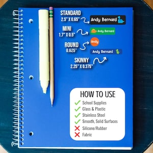 May include: A blue notebook with a white spiral binding. The notebook has a white and yellow pencil and a white marker on top of it. The notebook has text that says "STANDARD 2.5" X 0.65" MINI 1.7" X 0.5" ROUND 0.625" SKINNY 2.25" X 0.375" HOW TO USE School Supplies Glass & Plastic Stainless Steel Smooth, Solid Surfaces Silicone/Rubber Fabric".