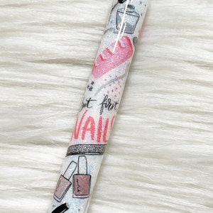 Peut inclure: Un stylo blanc avec une finition scintillante et un motif de c&oelig;ur rose. Le stylo a un capuchon noir et une pointe argent&eacute;e. Le stylo a un motif de flacons de vernis &agrave; ongles et le texte "N'oubliez pas le premier clou".