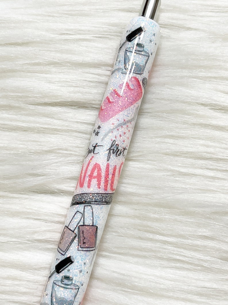 Peut inclure: Un stylo blanc avec une finition scintillante et un motif de c&oelig;ur rose. Le stylo a un capuchon noir et une pointe argent&eacute;e. Le stylo a un motif de flacons de vernis &agrave; ongles et le texte "N'oubliez pas le premier clou".
