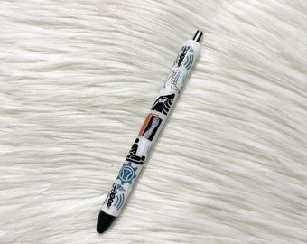 Könnte beinhalten: Ein weißer Stift mit schwarzer Kappe und verschiedenen bunten Designs auf dem Schaft. Die Designs beinhalten einen Stern, einen Kreis, eine Welle und ein geometrisches Muster.