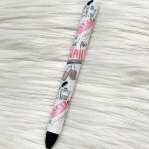 Peut inclure: Stylo blanc avec une pointe noire et des accents argent&eacute;s. Le stylo a un design paillet&eacute; rose et blanc avec des images de flacons de vernis &agrave; ongles, de limes &agrave; ongles et le texte "Just for Nails".