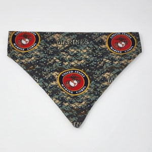 May include: A green, blue, and black camouflage bandana with the words "MARINES" and three United States Marine Corps logos. The logos are red, yellow, and blue.