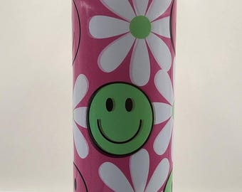 May include: A pink stainless steel tumbler with a white daisy and green smiley face pattern. The tumbler has a clear lid and a pink straw.