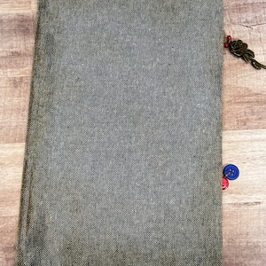 May include: A gray linen notebook with a decorative metal key charm and two buttons, one red and one blue.