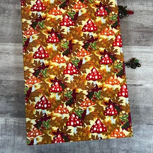 May include: A yellow fabric journal cover with a pattern of red and white mushrooms and brown leaves.