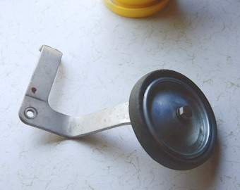 May include: A silver metal bracket with a black rubber wheel attached. The wheel has a silver metal hub with a screw in the center.