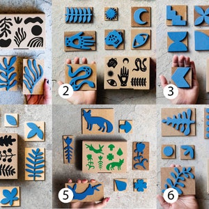 May include: Six sets of wooden stamps featuring a variety of designs, including abstract shapes, animals, plants, and geometric patterns. The stamps are painted in shades of blue and black.