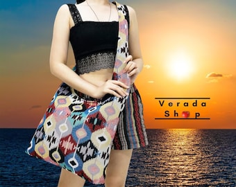 May include: A colorful, geometric patterned tote bag with a long strap worn over the shoulder. The bag is made of woven fabric and has a black and white striped pattern on the bottom.