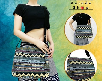 May include: A black and white striped bag with a geometric pattern in shades of blue, yellow, and red. The bag has a long strap and is worn over the shoulder. The bag is shown in two different positions, one on a person and one on a table. The text "Verada Shop" is visible in the image.