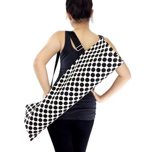 Puede incluir: Un porta-esterilla de yoga de lunares negros y blancos con una correa de hombro negra ajustable. El porta-esterilla est&aacute; hecho de lona y tiene una cremallera.