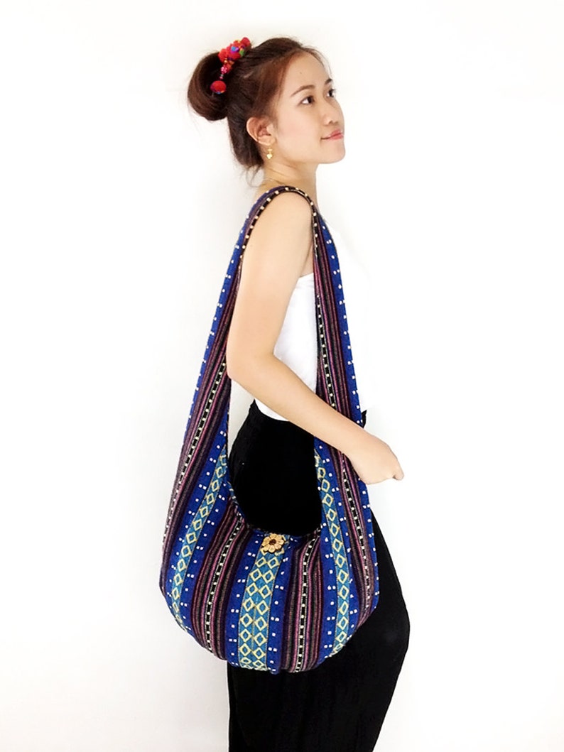 May include: A blue and black striped fabric tote bag with a flower design. The bag has a long strap and is worn over the shoulder.