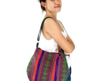 May include: A green, purple, orange, and white striped fabric tote bag with a green leather strap. The bag has a woven pattern with green floral designs.