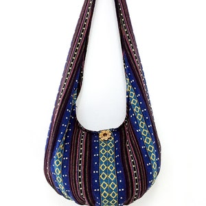 May include: A blue and purple striped fabric tote bag with a floral design. The bag has a long strap and is made of a woven fabric.