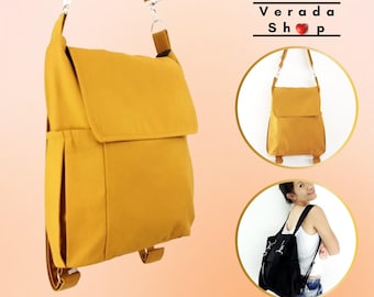 May include: A mustard yellow canvas backpack with a flap closure and adjustable straps. The backpack can be worn as a crossbody bag or a shoulder bag. Verada Shop is printed on the image.