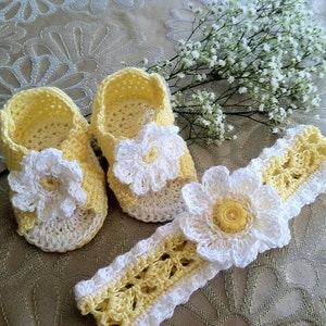 May include: A set of crocheted baby shoes and headband in yellow and white with a daisy flower design.