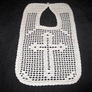 May include: A white crocheted baby bib with a cross design and a pearl button at the top.