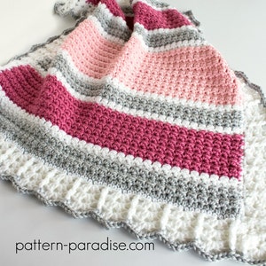 May include: A crocheted baby blanket with a scalloped edge in white, pink, and gray stripes. The blanket is made with a textured stitch and has a delicate, feminine feel.