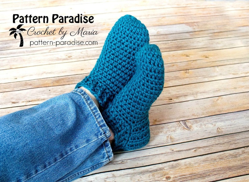 May include: A pair of teal blue crocheted slipper socks. The socks are worn on a person's feet, with the ankles showing blue jeans.