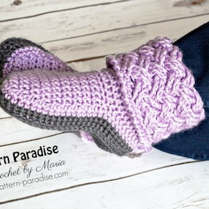 May include: Purple and gray crocheted slipper boots with a cable knit pattern. The boots are worn on a person's feet. The text "Pattern Paradise Crochet by Maria pattern-paradise.com" is visible in the image.