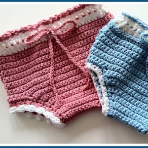 Puede incluir: Dos cubiertas de pañal de ganchillo, una rosa y otra azul, con ribete blanco. Las cubiertas tienen un lazo en la cintura y están hechas con un patrón de punto sencillo.