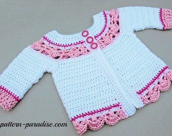 May include: White crocheted baby cardigan with pink trim and buttons. The cardigan has a scalloped edge and a delicate crochet pattern.