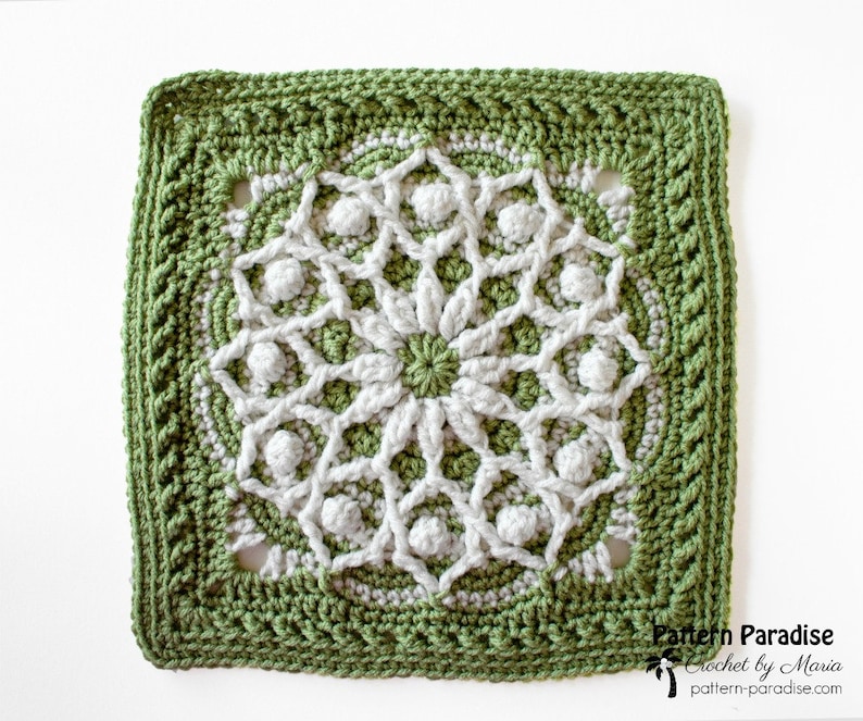May include: A square, handmade crochet piece featuring a central floral design in white and light green, surrounded by a detailed border in a darker green. The piece has a textured appearance, with visible stitches and raised elements. The text "Pattern Paradise" is visible in the bottom right corner.
