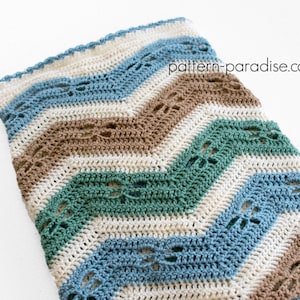 May include: A crocheted chevron blanket in shades of blue, green, brown, and white. The blanket has a lacy pattern and is made with a soft yarn.