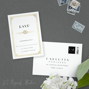 May include: Gold framed RSVP card with a gold geometric design. The text "RSVP" is in a bold, sans-serif font. The card includes a line for the guest's name and two options for responding: "Joyfully Accepts" and "Regretfully Declines". The card also includes the text "Please respond by April 21".