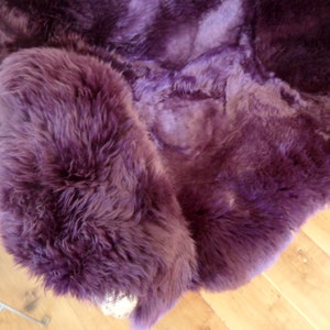 May include: A plush purple sheepskin rug with a soft, fluffy texture.