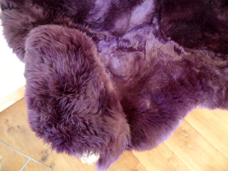 May include: A plush purple sheepskin rug with a soft, fluffy texture.