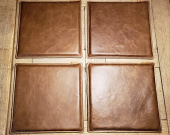 May include: Four brown leather square seat cushions with a stitched edge.