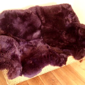 May include: A plush, deep purple sheepskin rug, perfect for adding warmth and texture to a living room or bedroom.