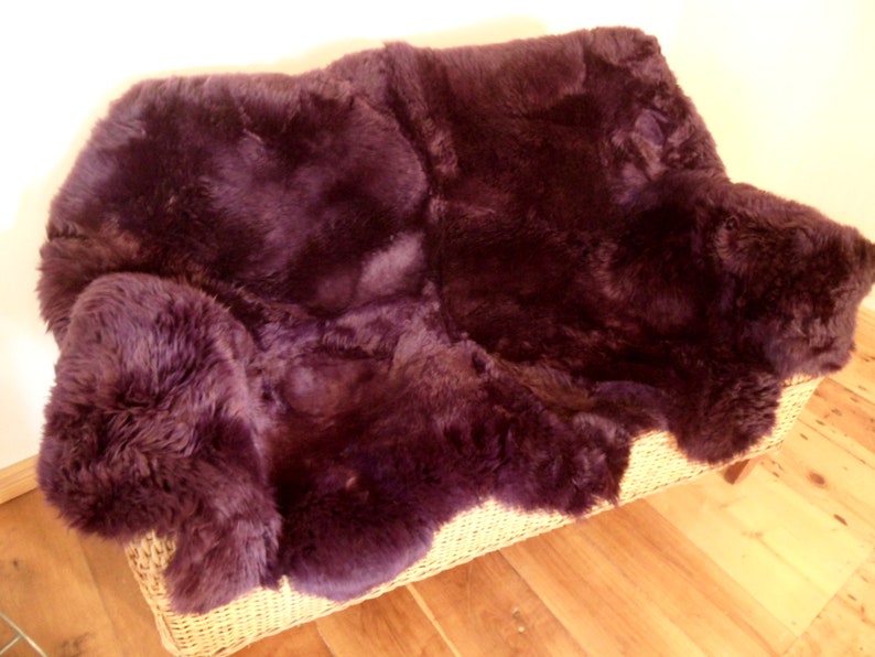 May include: A plush, deep purple sheepskin rug, perfect for adding warmth and texture to a living room or bedroom.
